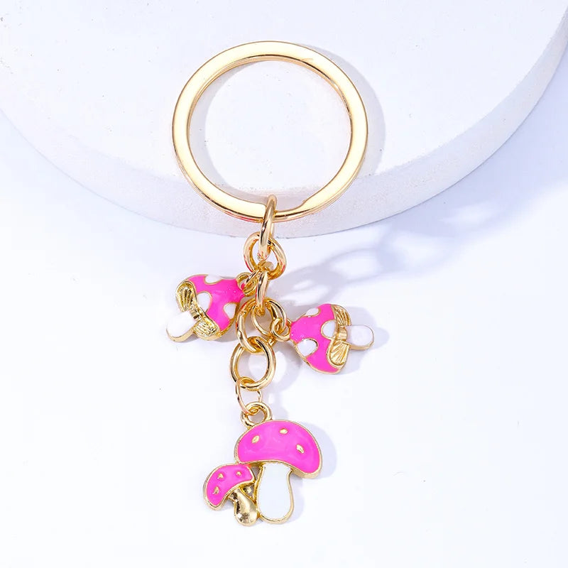 Gold keychain with pink mushroom and elephant charms on a white background