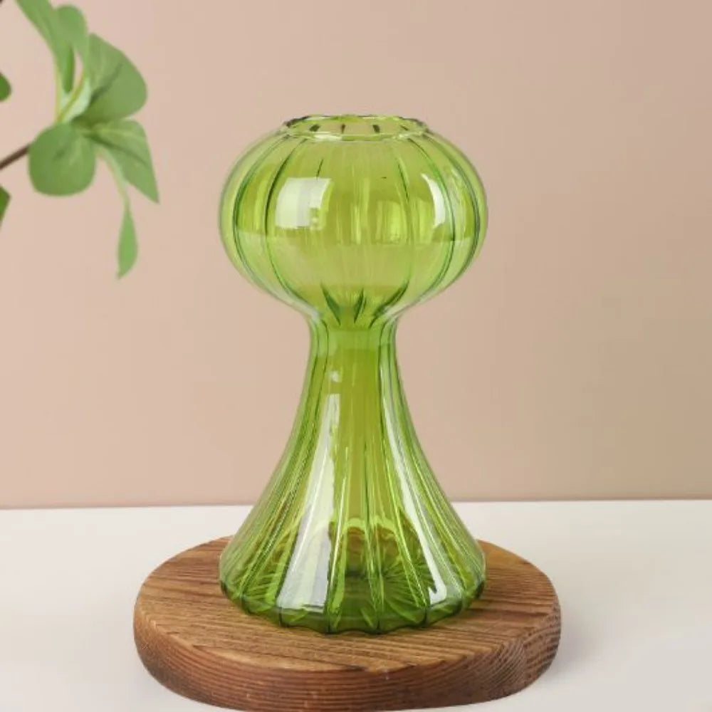 Green glass vase on a wooden base with a beige background