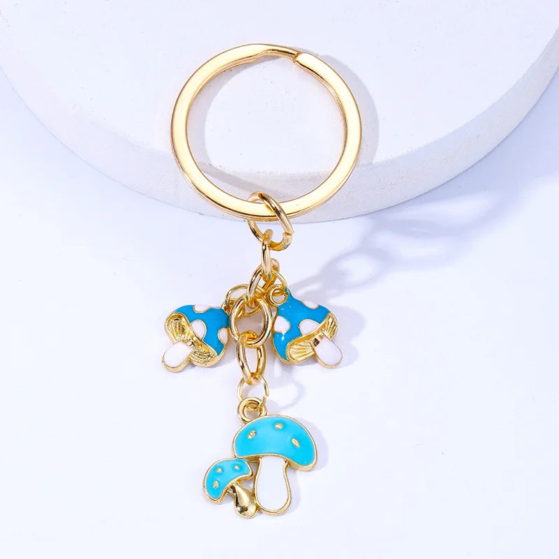 Gold keychain with blue mushroom charms on a white background