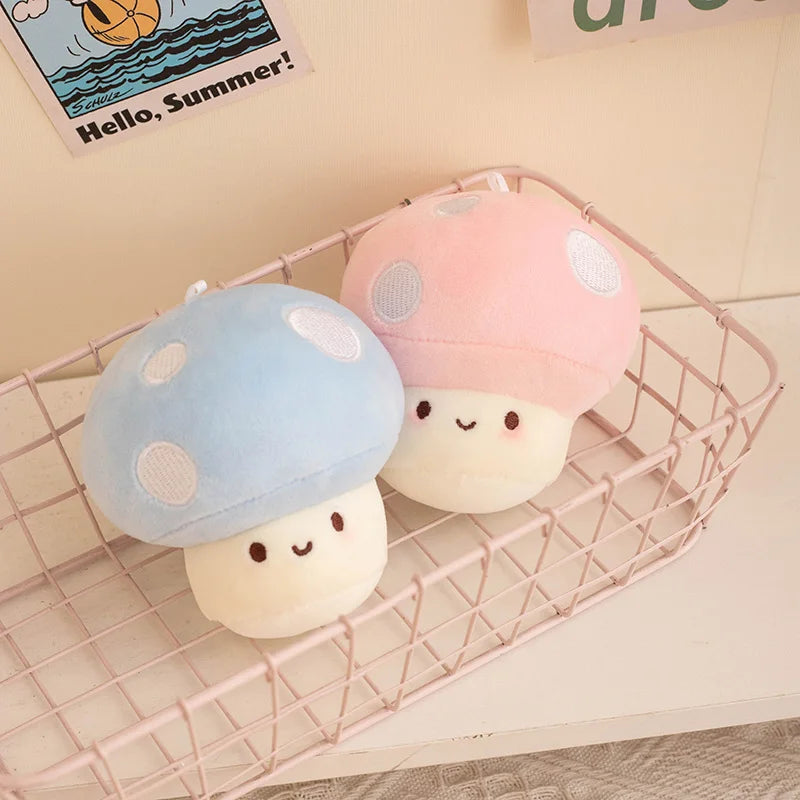 Two cute plush mushroom toys in pink and blue on a wire basket with a 'Hello, Summer!' card in the background.