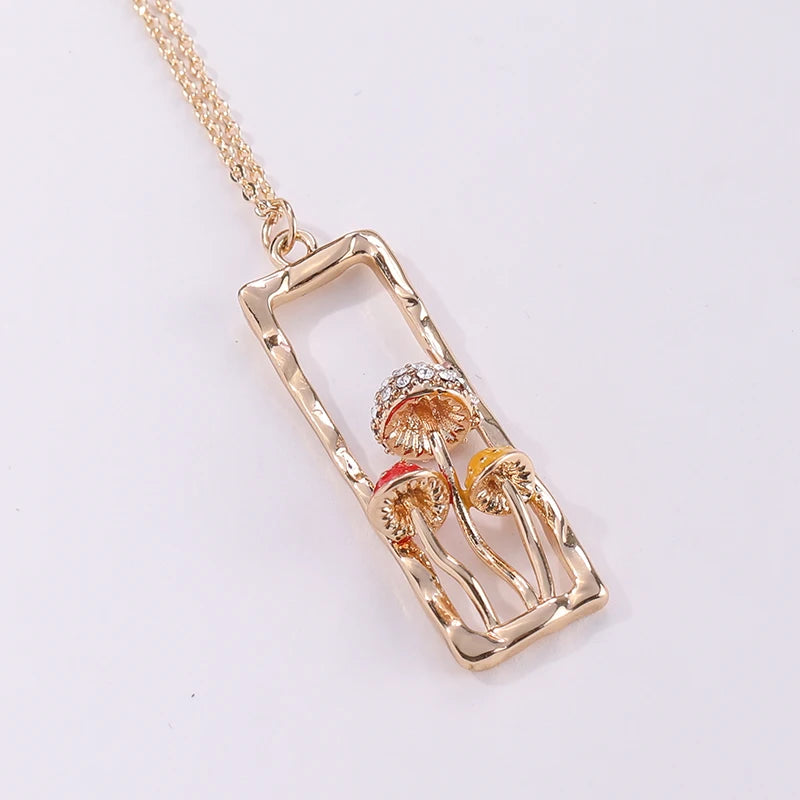 Gold necklace with a rectangular pendant featuring two mushrooms on a white background