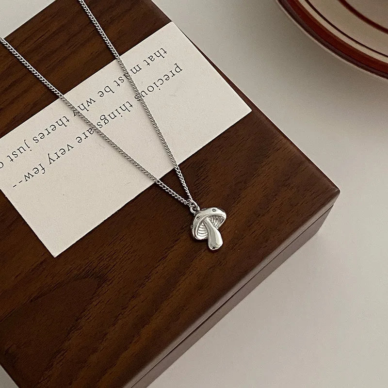 Silver necklace with a mushroom pendant on a wooden box