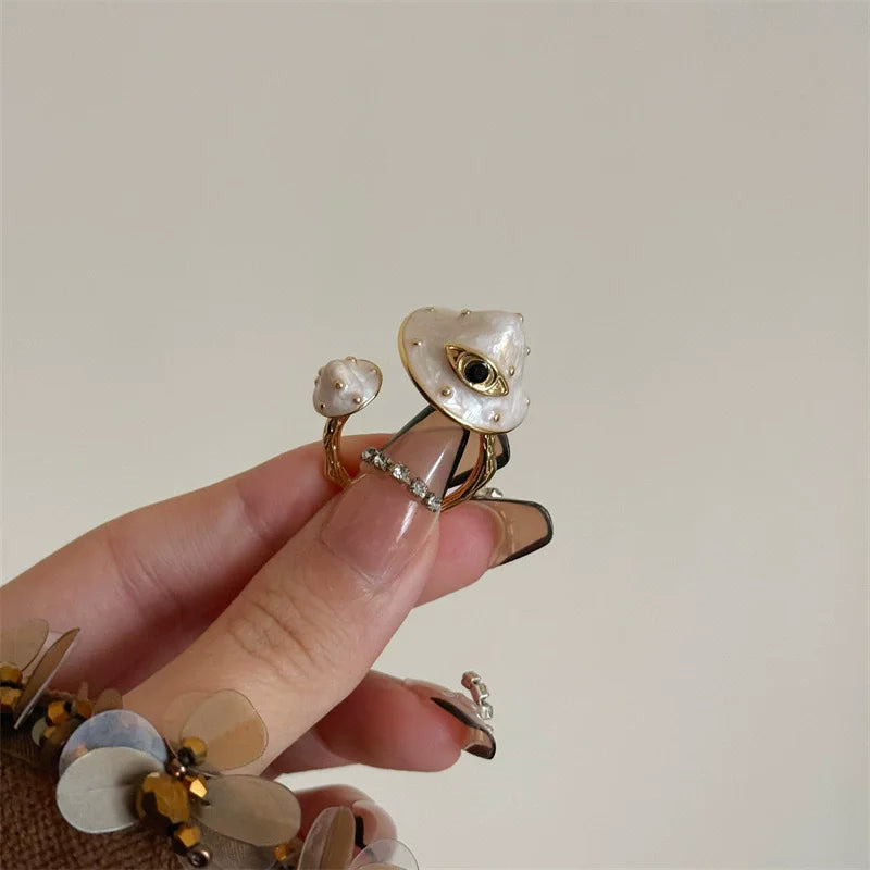 Gold and pearl earring held between fingers against a neutral background
