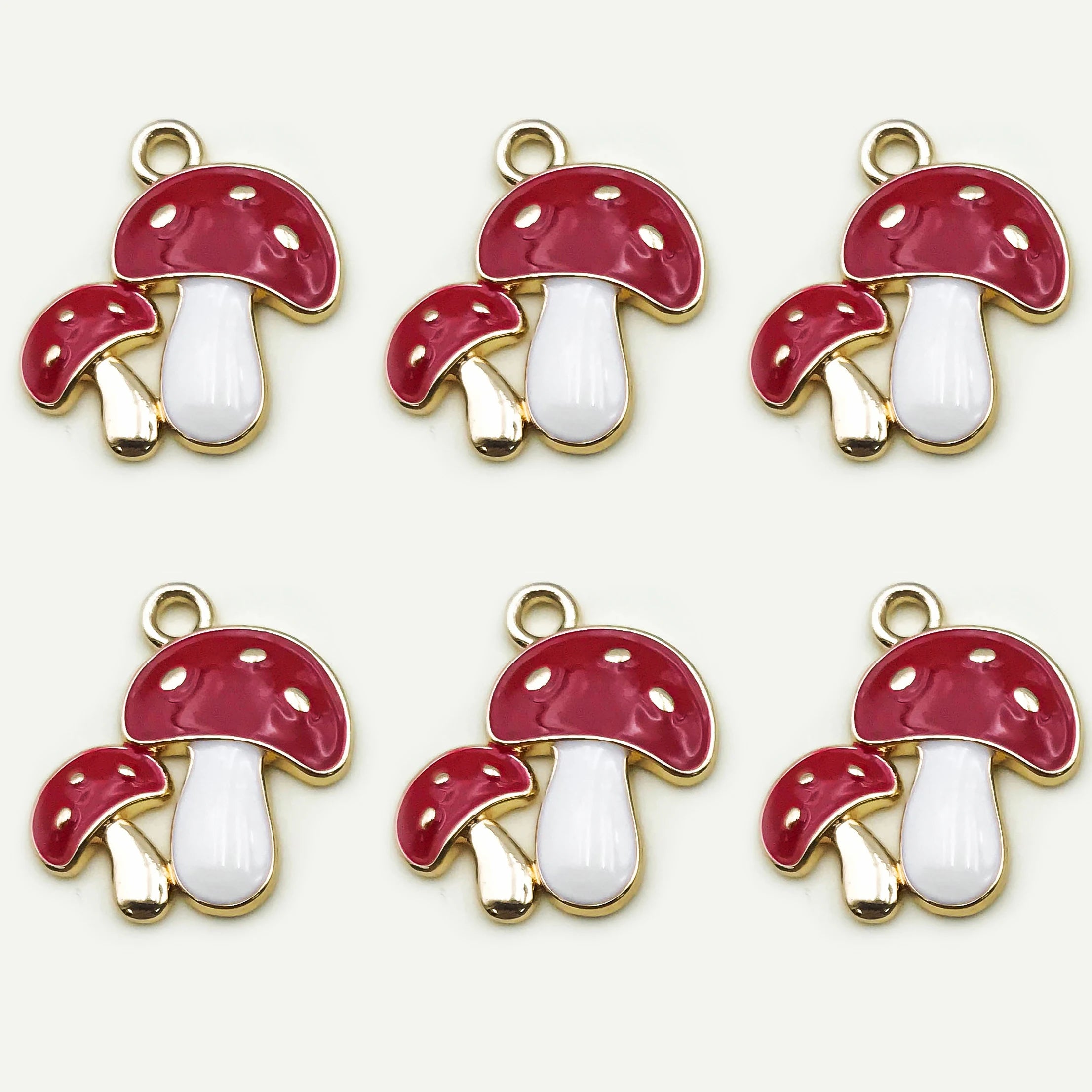 Six red and white mushroom-shaped charms with gold accents on a white background