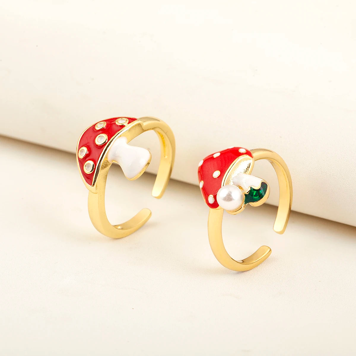 Gold earrings with red and white polka dot designs on a beige background