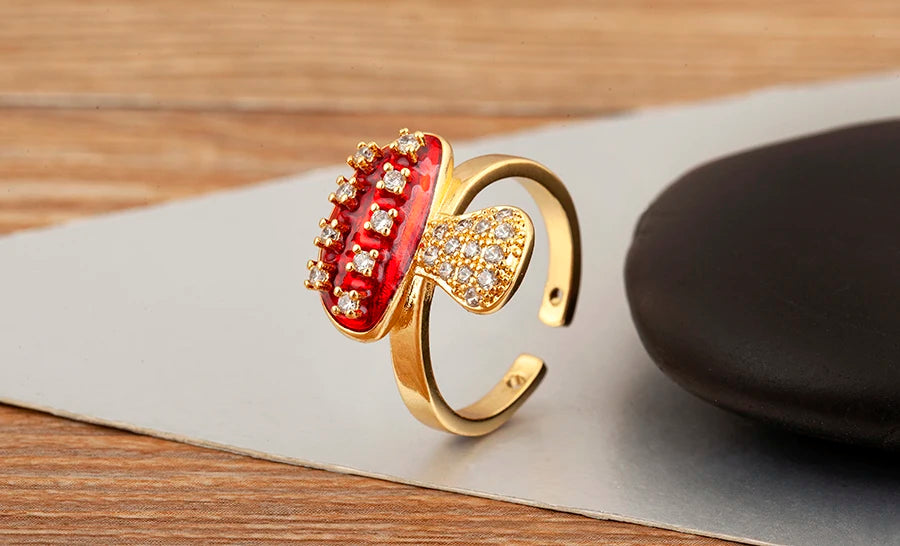 Gold ring with red gemstone and diamond accents on a wooden surface