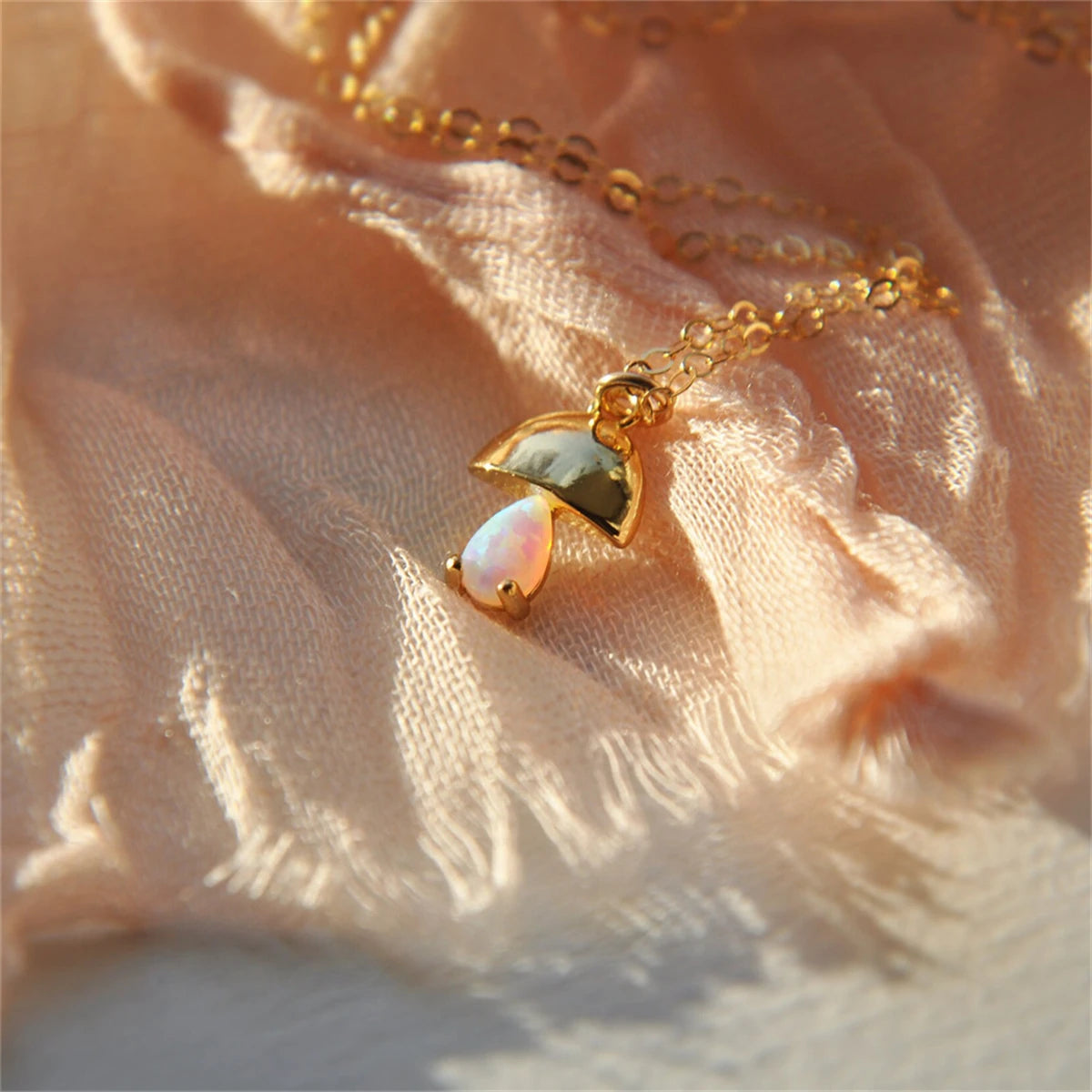 Gold necklace with a heart-shaped pendant on a soft fabric background