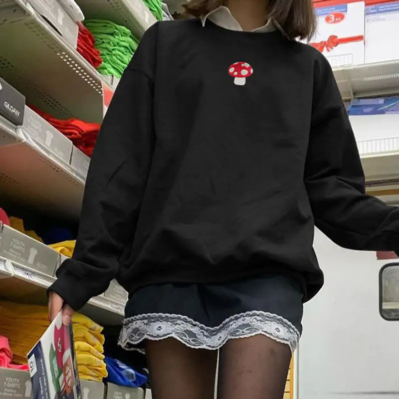 Person wearing a black sweatshirt with a red and white mushroom design in a store setting.
