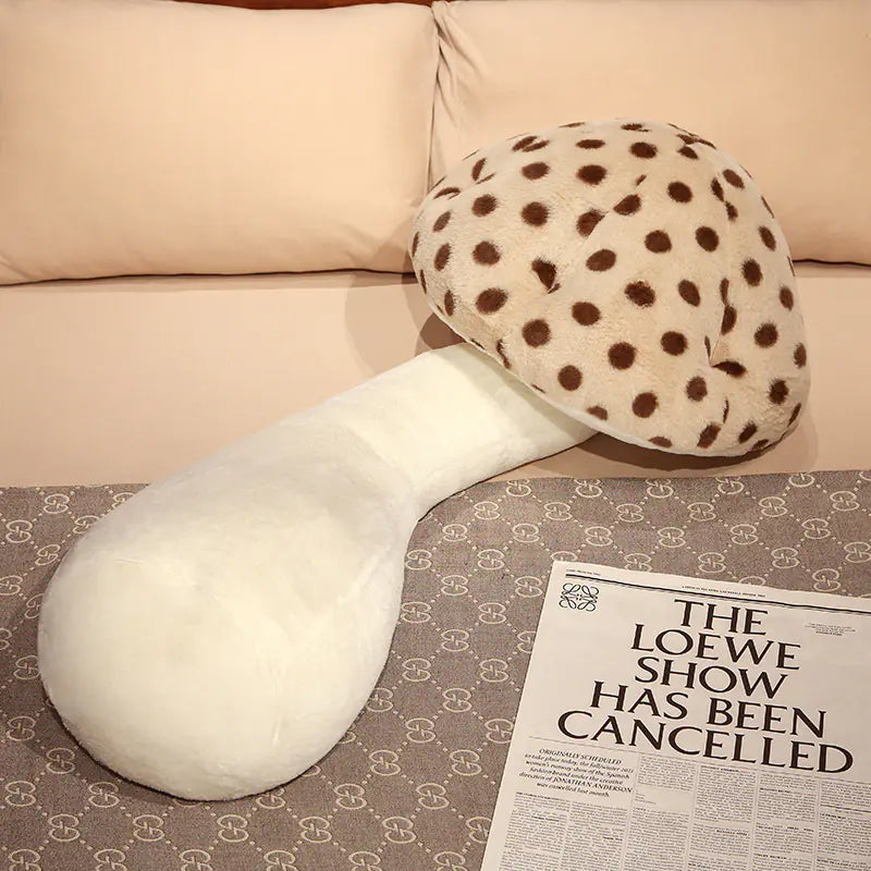 Two plush mushroom-shaped cushions on a patterned surface with a newspaper underneath.