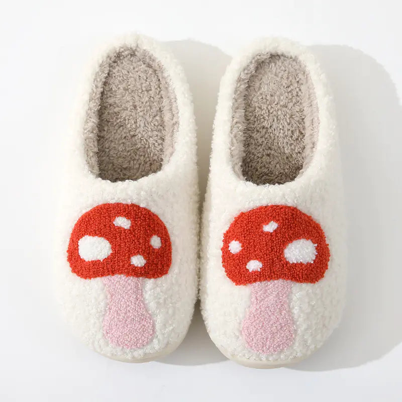 Pair of white slippers with red mushroom design on a white background