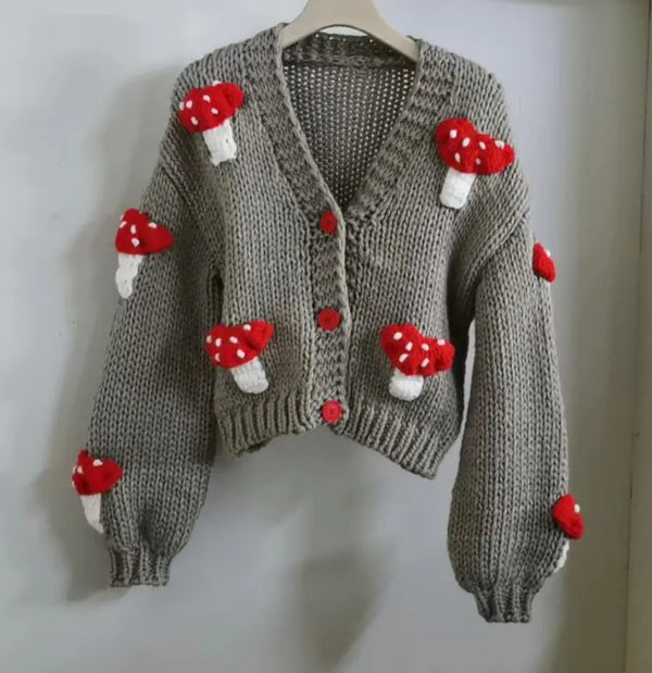 Knitted sweater with red mushroom decorations on a white background