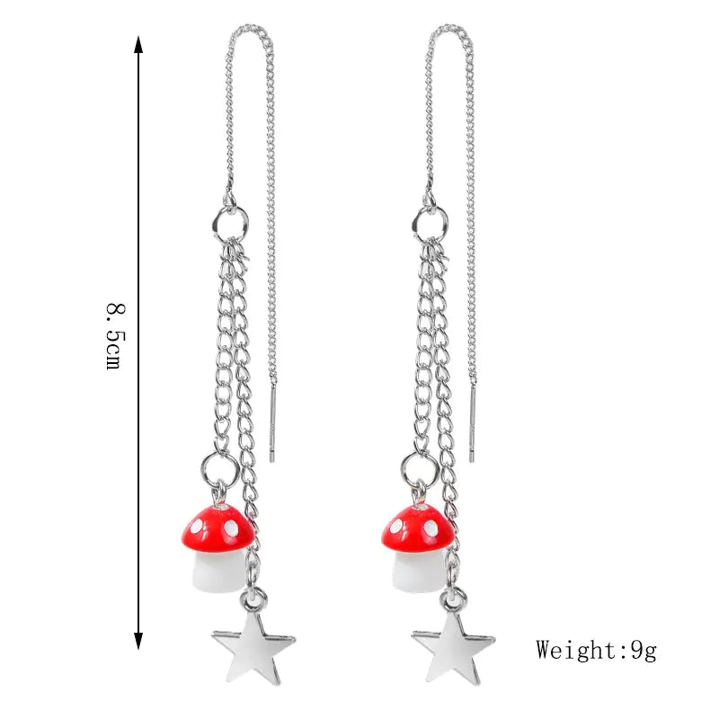 Pair of earrings with red mushroom and star charms on a white background