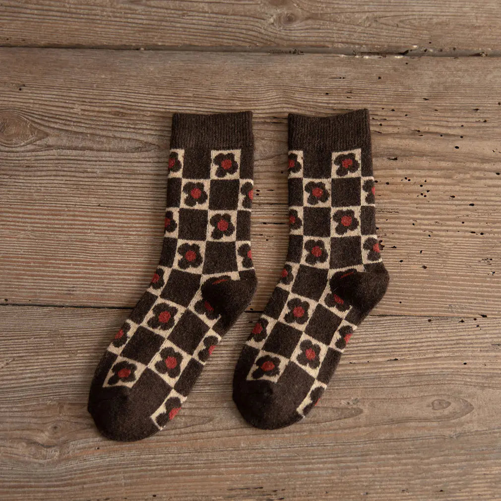 Pair of checkered socks with red flowers on a wooden surface