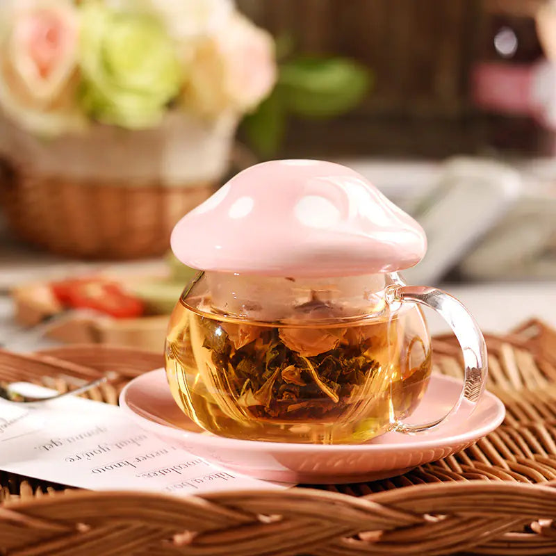 Clear glass teacup with pink lid filled with tea leaves on a woven surface.