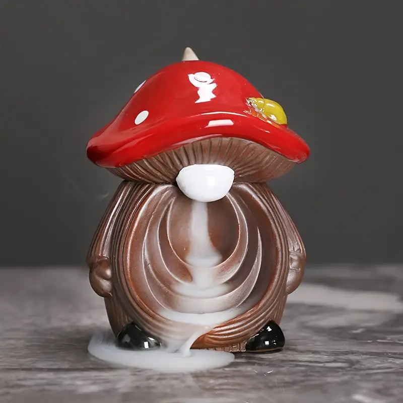Mushroom-shaped incense burner with a red cap on a gray surface