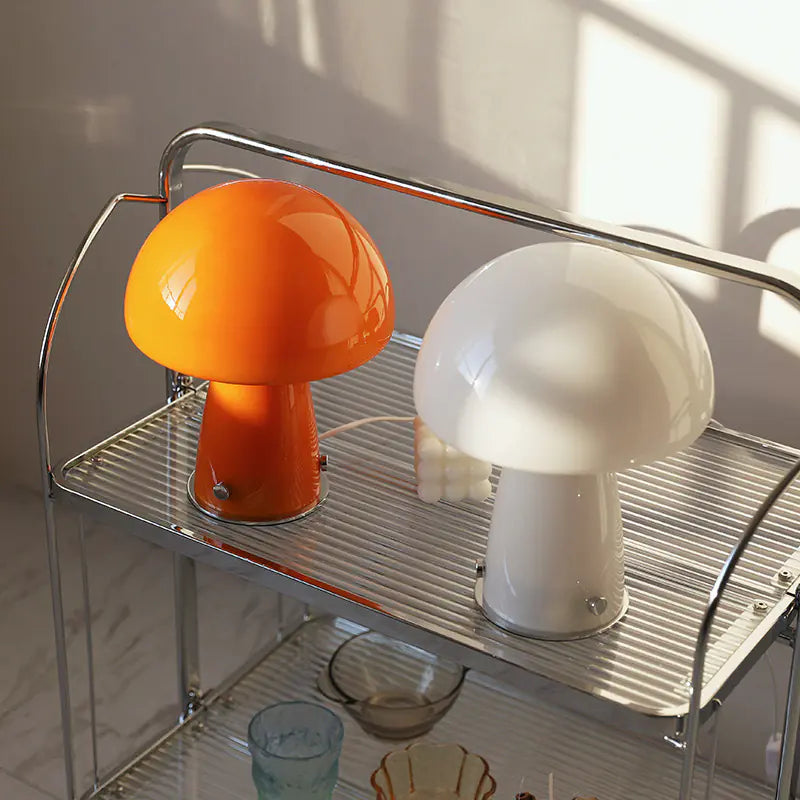 Two mushroom-shaped lamps, one orange and one white, on a metal shelf.