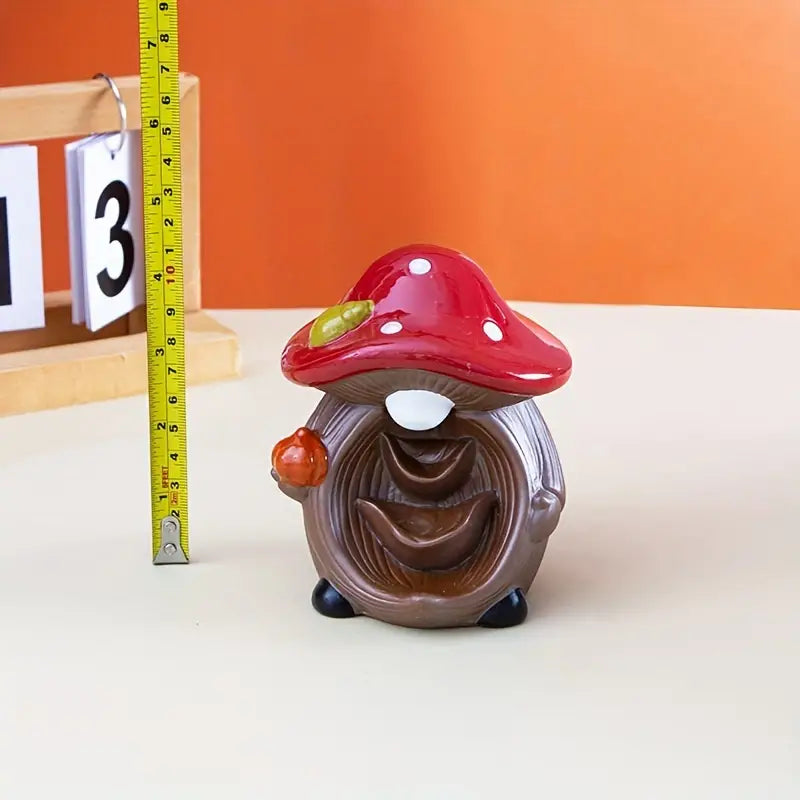 Mushroom-shaped decorative item with a red cap and brown body on a white surface.