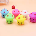 Colorful mushroom-shaped toys with smiling faces on a light pink background