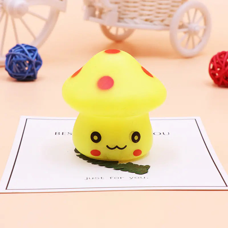 Yellow squishy toy shaped like a mushroom on a light surface with decorative elements.
