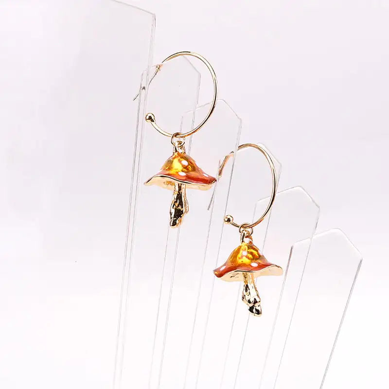 Mushroom-shaped earrings on a clear stand against a white background
