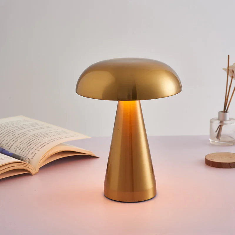 Gold table lamp on a surface with an open book and decorative items in the background