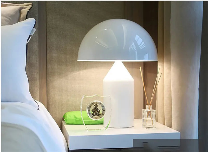 White table lamp on a nightstand next to a bed with pillows.