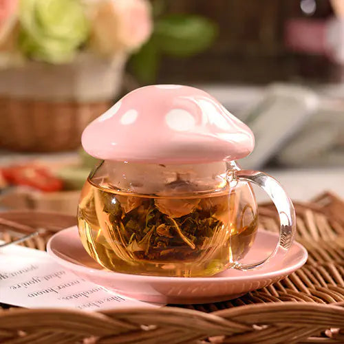Glass teacup with pink lid containing tea leaves on a pink saucer, blurred background