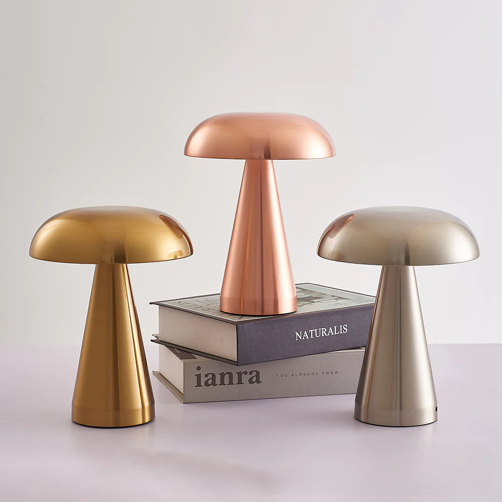 Three metallic mushroom-shaped lamps on books with a plain background