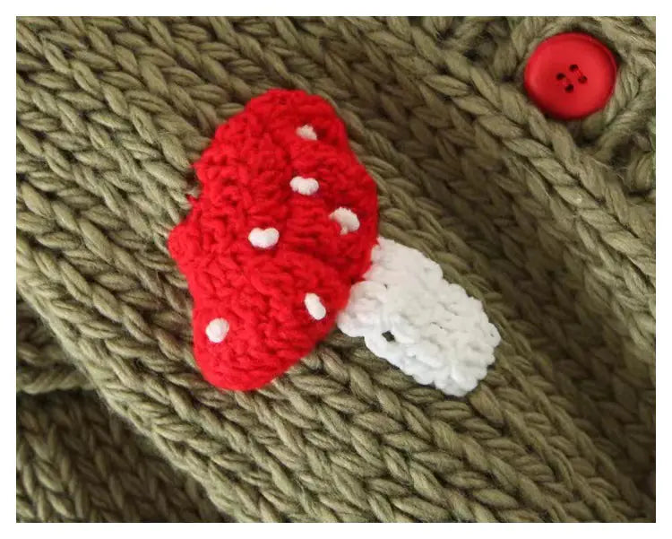 Knitted red and white mushroom patch on a textured fabric background