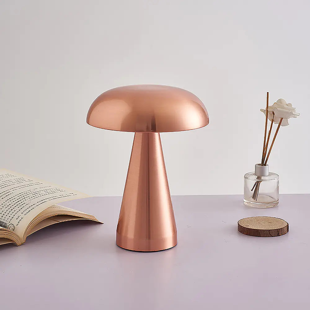 Copper table lamp on a surface with an open book and small vase in the background