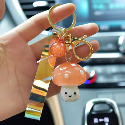 Keychain with mushroom charm held by a hand in a car interior.